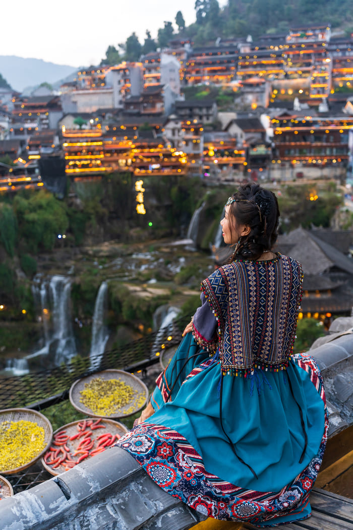 una persona femenina sentada viendo a lo lejos la ciudad de Lijiang
